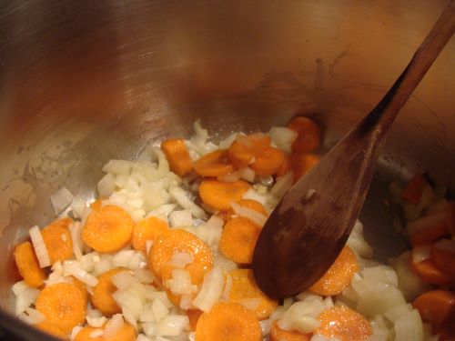 Chopped carrots and onions sauteing in a pot