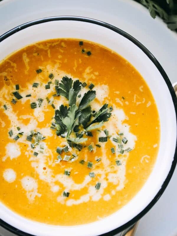 Overhead view of butternut squash soup served in a bowl garnished with fresh herbs.