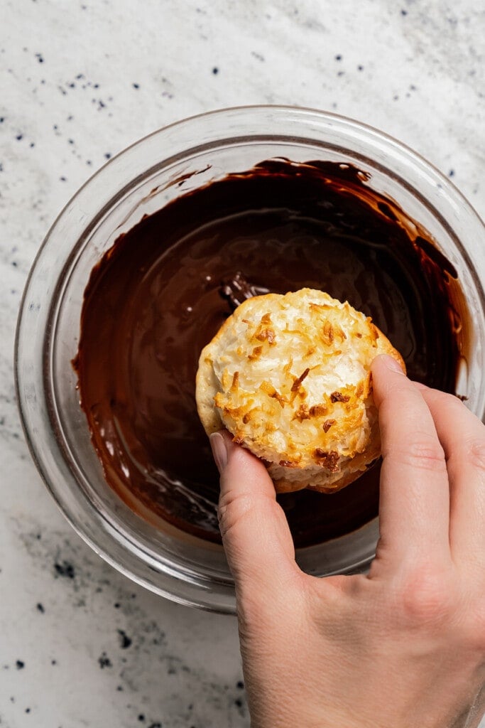 Dipping the macaroons into melted chocolate. 