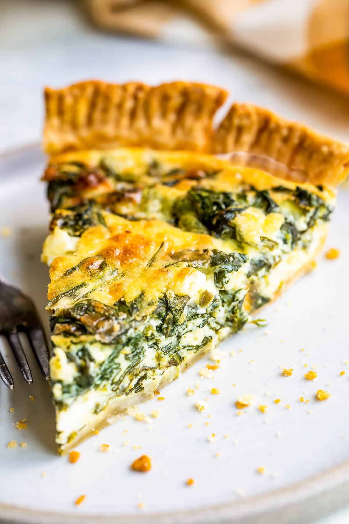 Slice of spinach quiche on a plate.