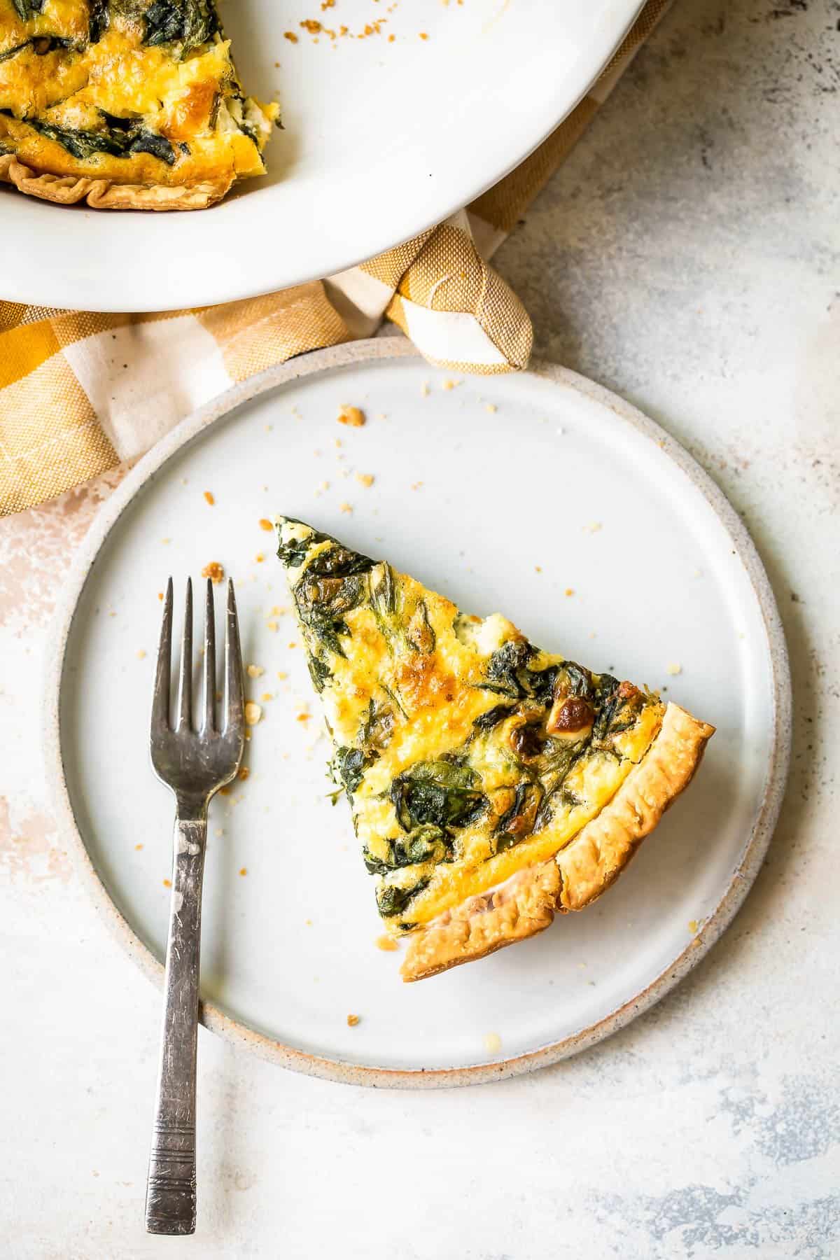 Spinach quiche slice with a fork.