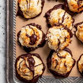 Macaroons arranged on a parchment paper lined baking sheet.