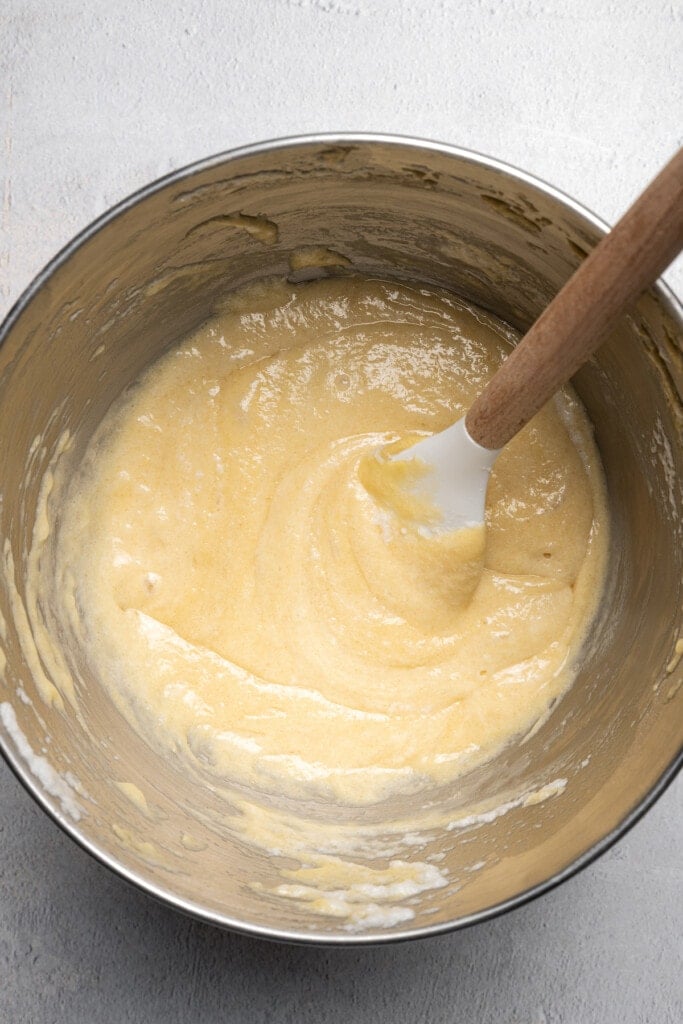 Pineapple upside down cake batter in a large bowl with a wooden spoon.