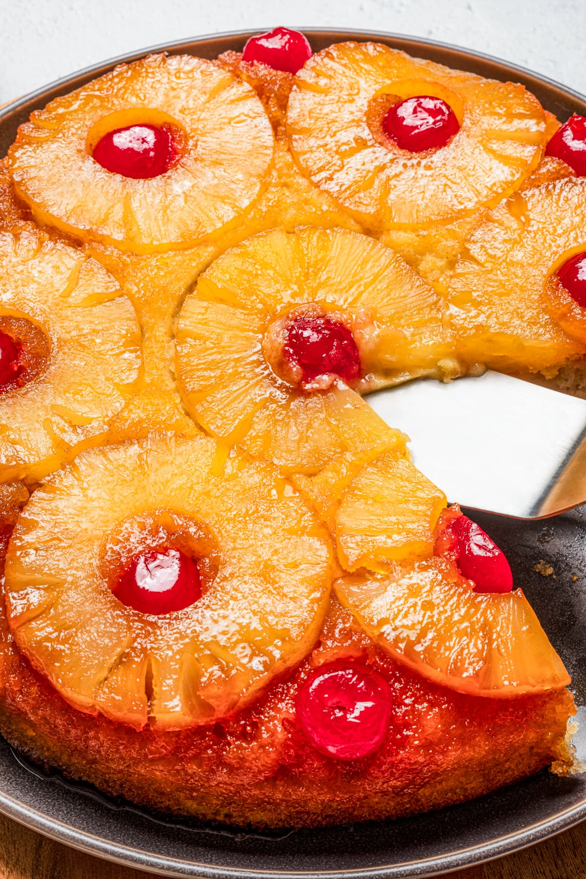 Close up of a pineapple upside down cake with a slice missing.