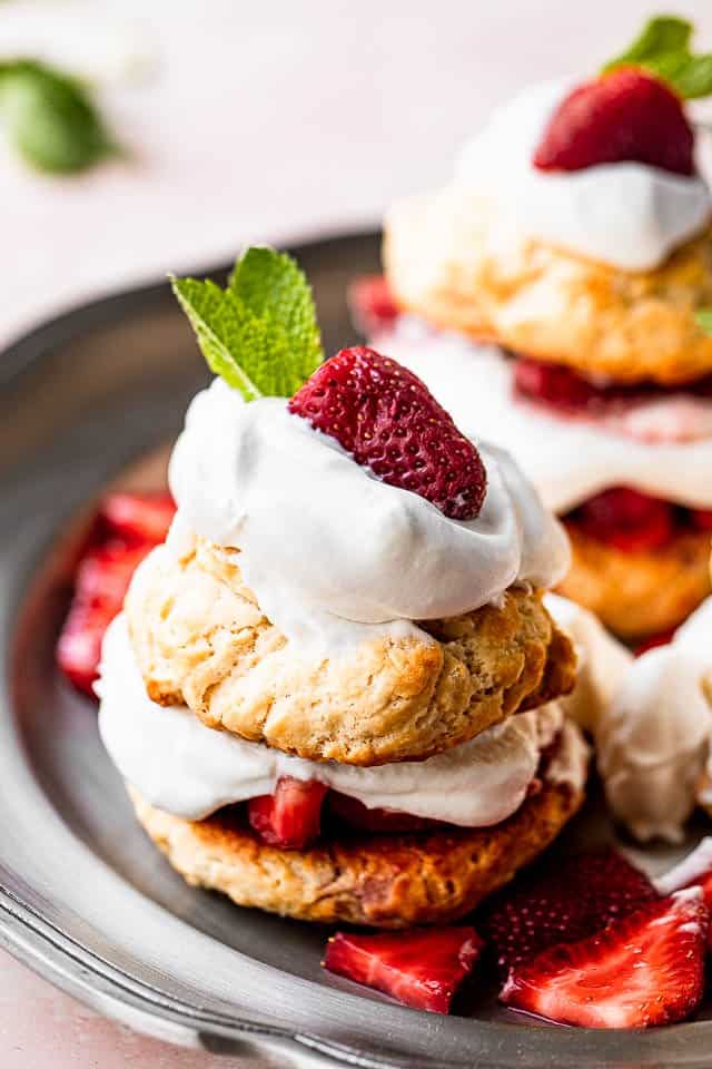 Shortcake garnished with whipped cream, strawberry, and a fresh mint leaf.