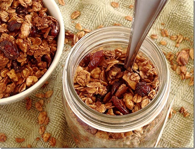 Chocolate granola in a jar with a spoon.