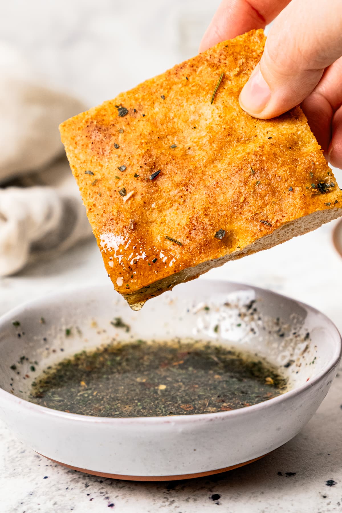 Dipping a slice of bread in olive oil with herbs.