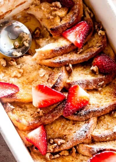 Baked French toast with sliced strawberries and maple syrup.