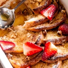 Breakfast casserole with powdered sugar and sliced strawberries.