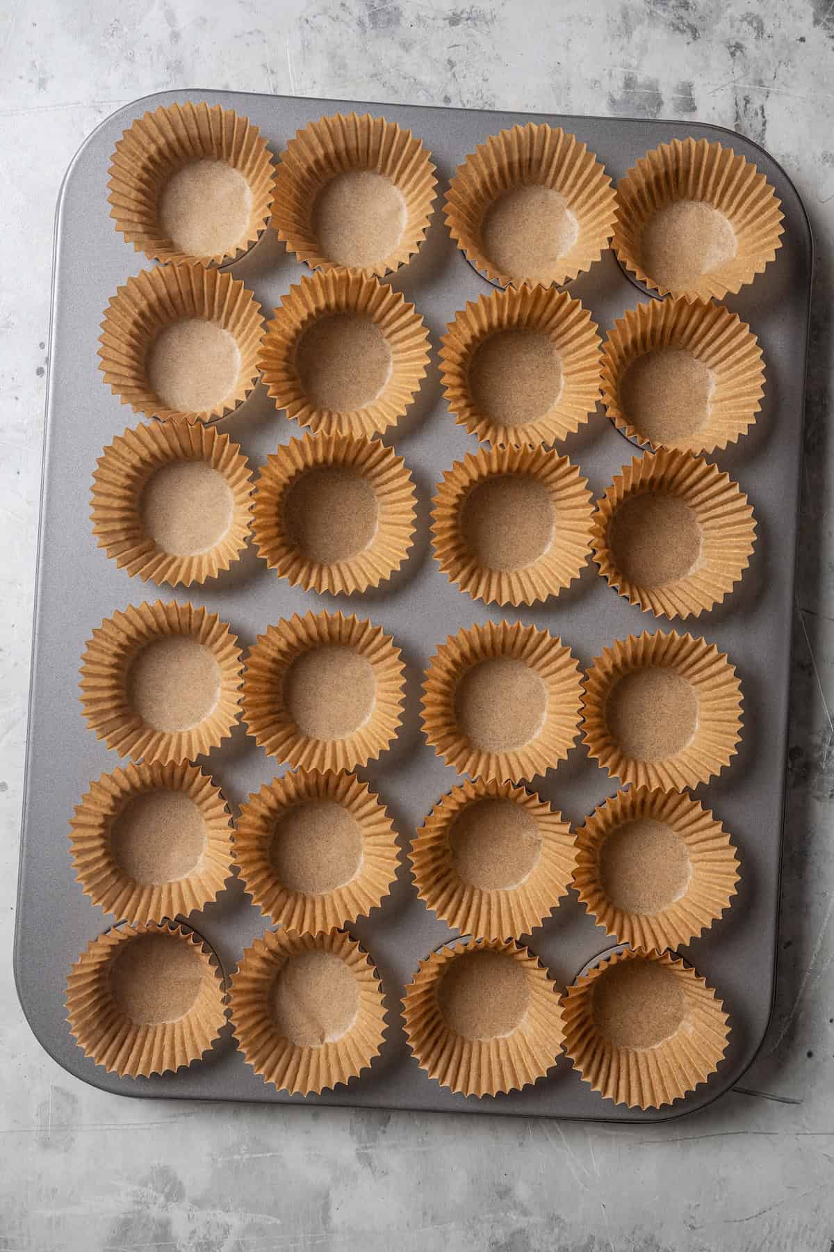 Overhead view of a 24-cup mini muffin pan lined with cupcake liners.