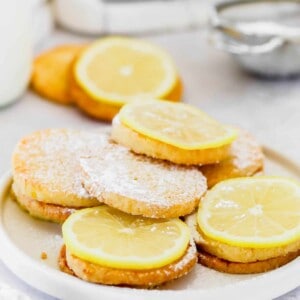 A plate of lemon cookies topped with lemon slices and dusted with powdered sugar.