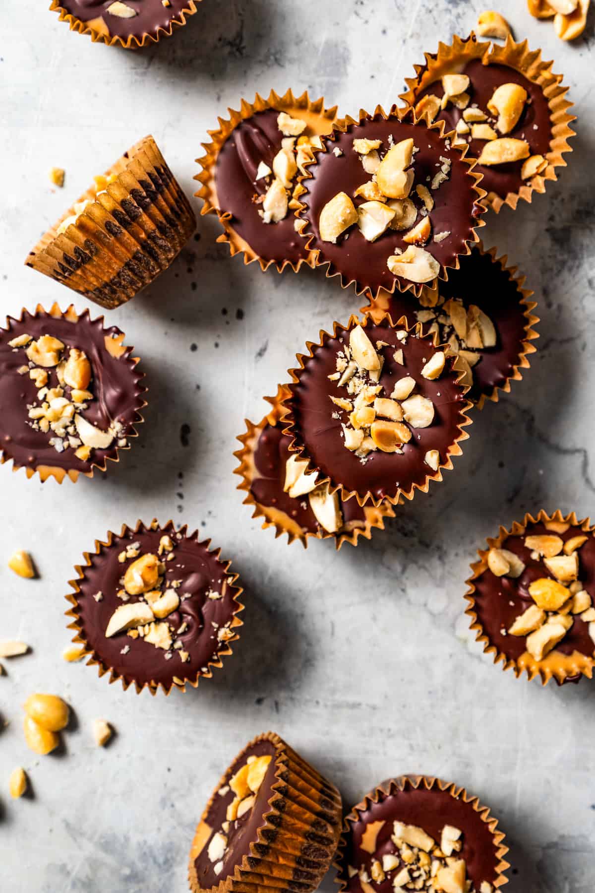 Overhead view of assorted homemade peanut butter cups topped with crushed roasted peanuts.