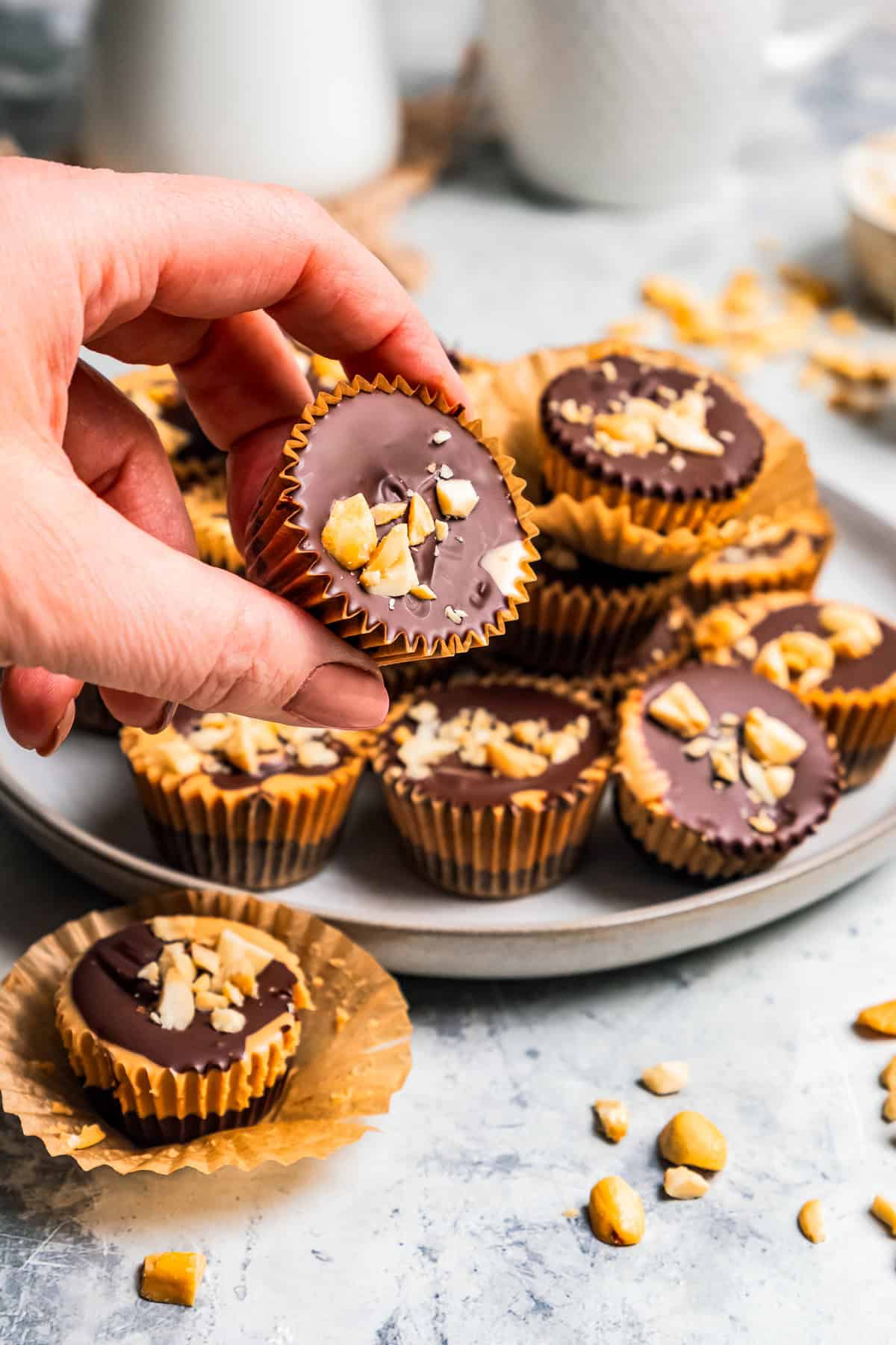 A hand lifting a peanut butter cup from a pile on a plate.