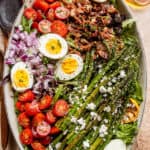 asparagus, eggs, bacon, and tomatoes on top of lettuce leaves in a long oval plate