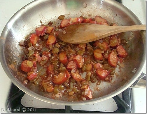 Rhubarb cooking in a skillet with a wooden spoon