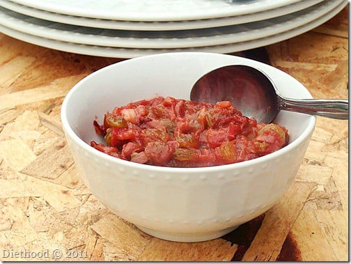 A white bowl of rhubarb chutney with a spoon