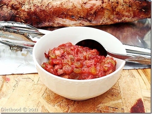 A white bowl of rhubarb chutney with a spoon