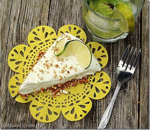 a slice of frozen mojito pie topped with a slice of lime and crushed pretzels.