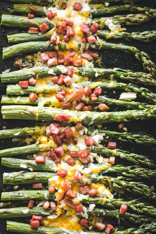 Roasted asparagus with bacon and cheese on a tray.