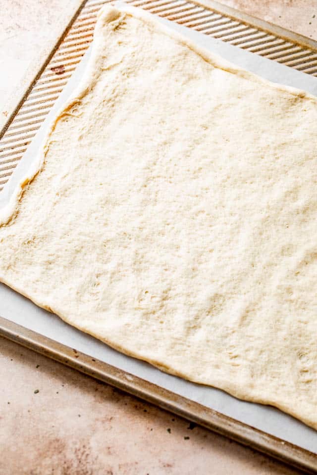 raw pizza dough on top of cookie sheet