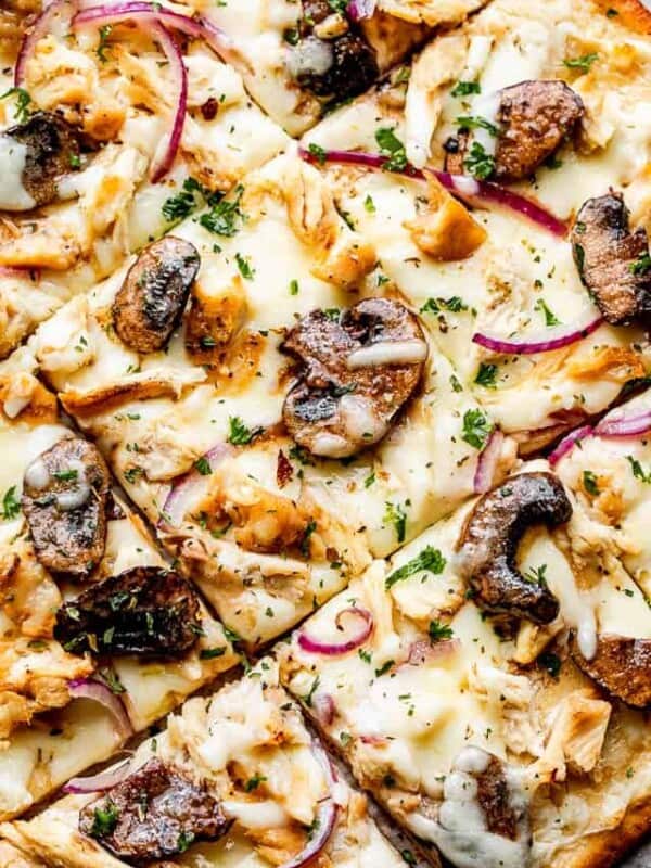 top view of a grilled pizza topped with Cheese, mushrooms, chicken, and red onions