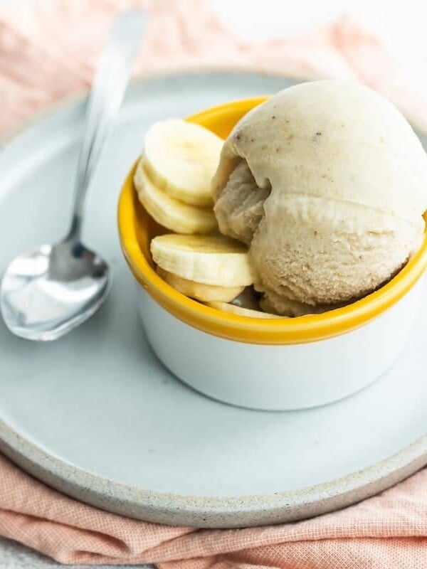 Spoon on a plate with a bowl of frozen yogurt.