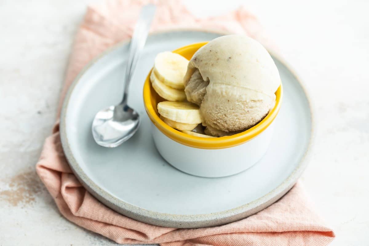 Spoon on a plate with a bowl of frozen yogurt.