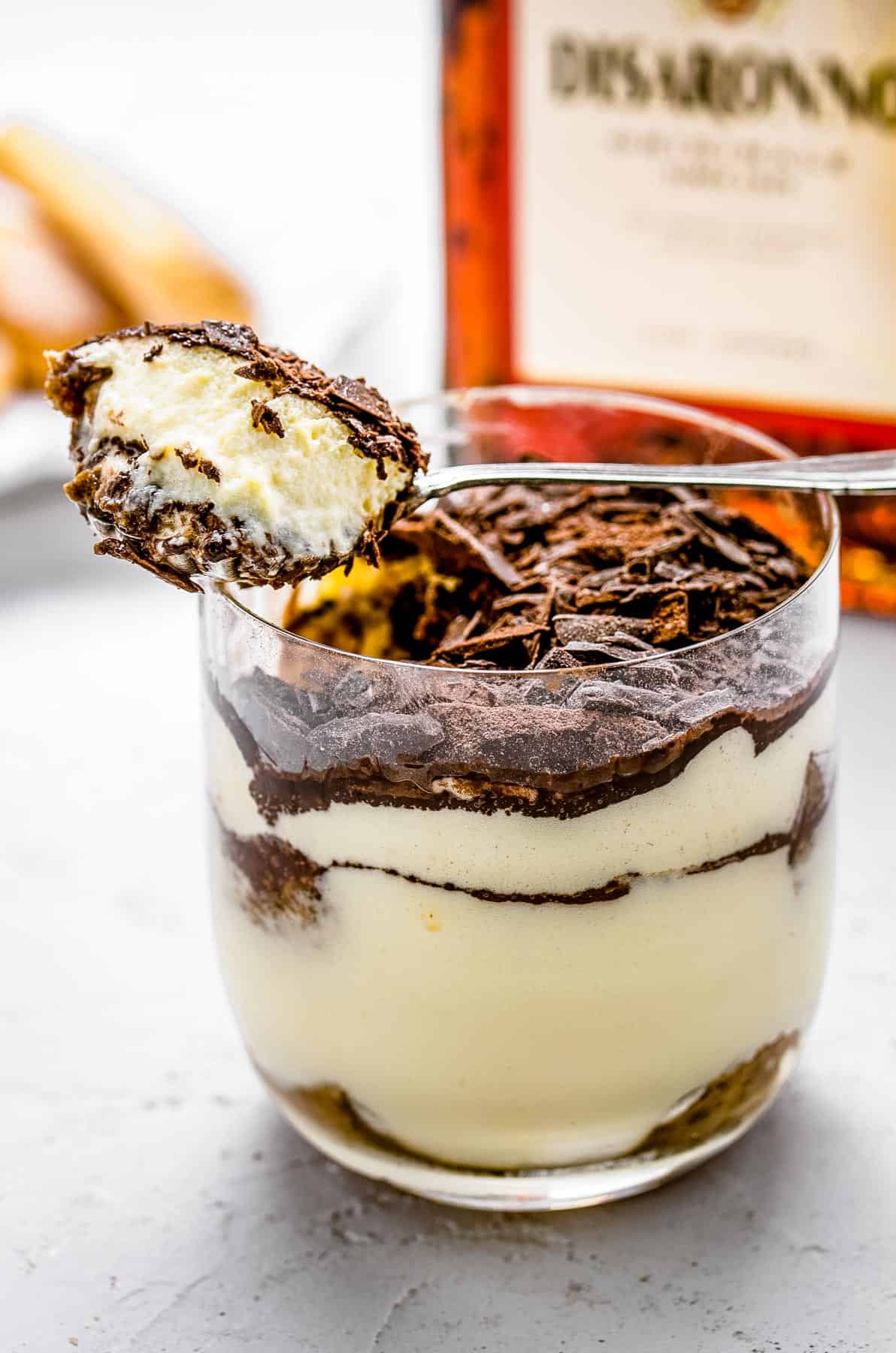 A spoonful of tiramisu is scooped from the glass.