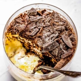 overhead shot of tiramisu in a glass with a spoon inside of it.