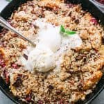 Overhead view of a homemade Brown Betty with peaches and cherries, topped with melted ice cream in a skillet.