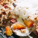 Close up of ice cream melting over a warm cherry peach Brown Betty in a skillet.