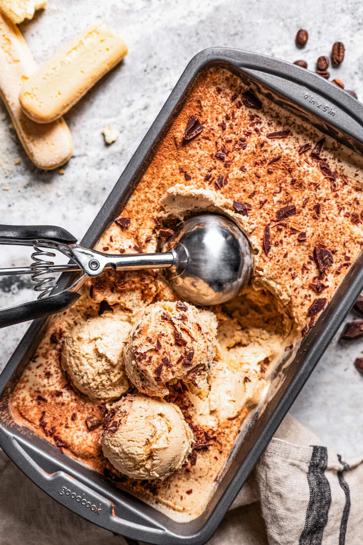 Overhead view of tiramisu ice cream in a loaf pan, with an ice cream scoop.
