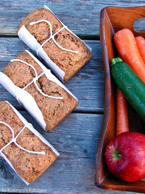 Fruit and veggie quick bread loaves next to a basket of fresh veggies.