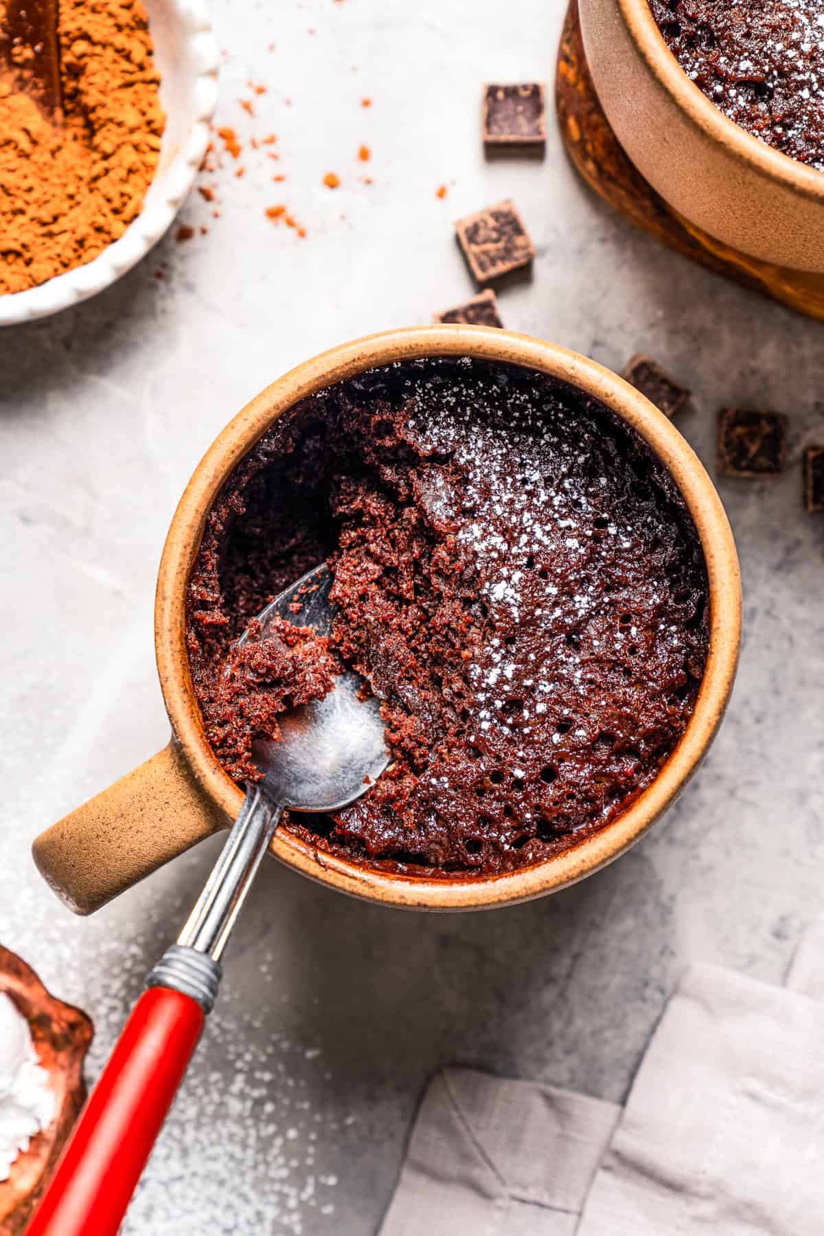 Overhead view of a spoon resting in a partially eaten chocolate mug cake.