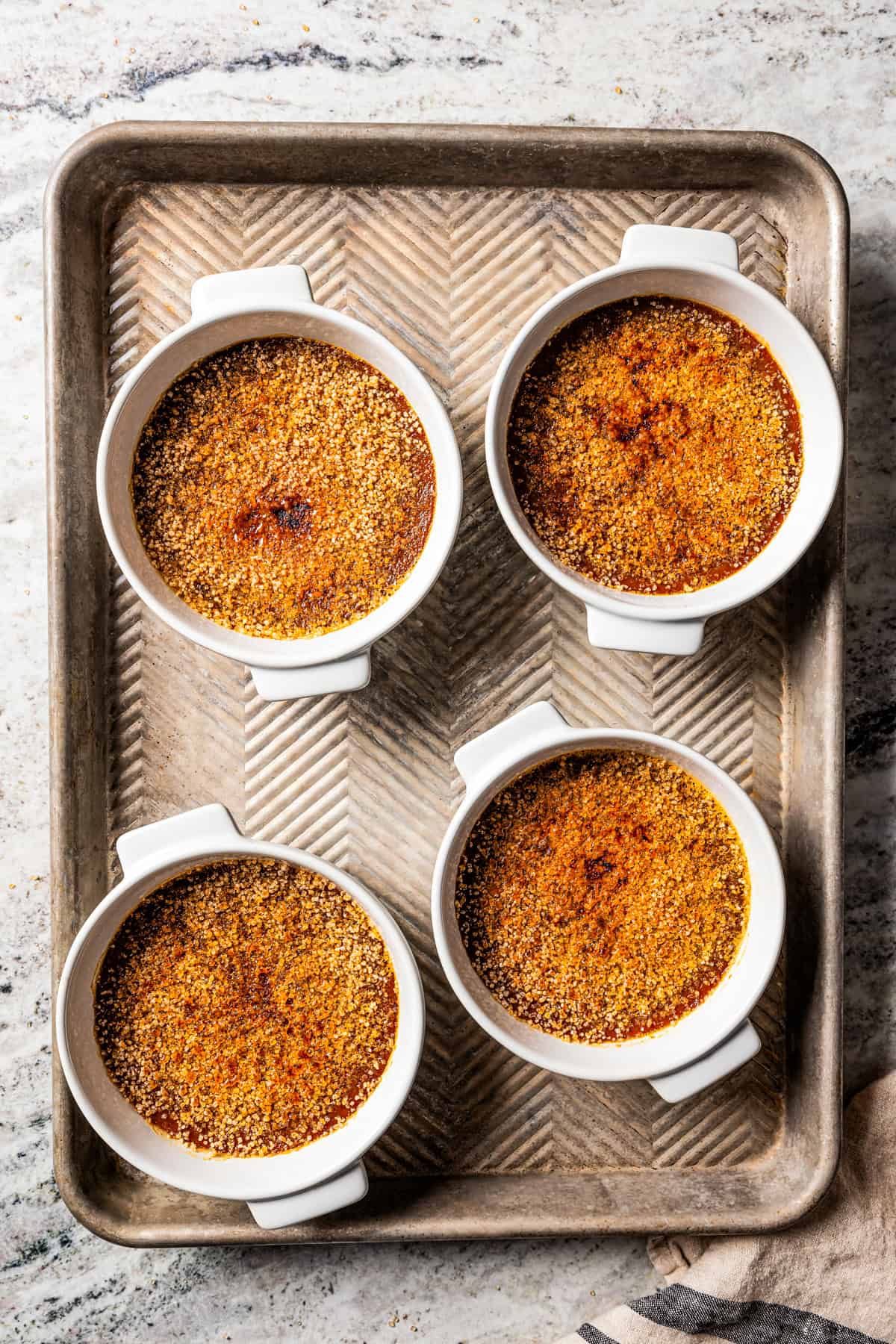 Crème brûlée in ramekins set on a metal tray.