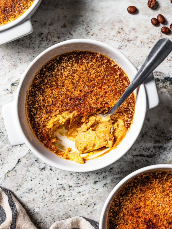 Overhead view of a spoon resting in a ramekin of coffee crème brûlée.