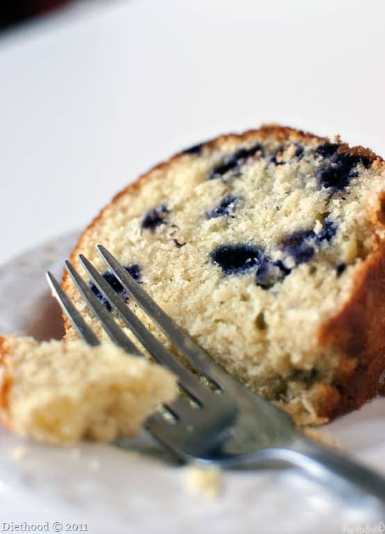 Slice of lemon pound cake with fresh blueberries in it.