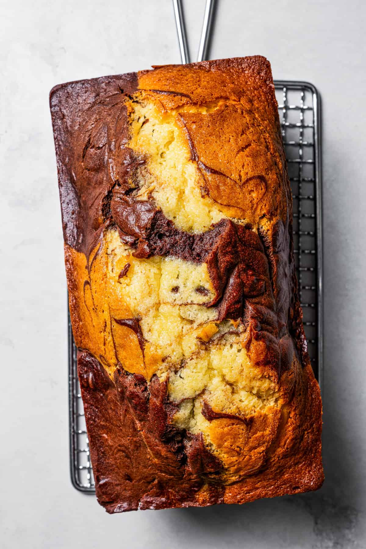 Yellow and brown marble cake set on a cooling rack.