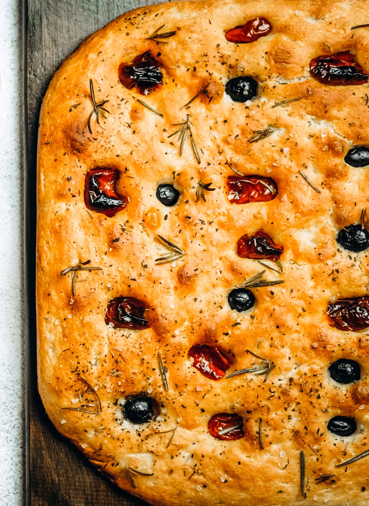 Traditional Italian Focaccia bread topped with tomatoes, olives, and rosemary.