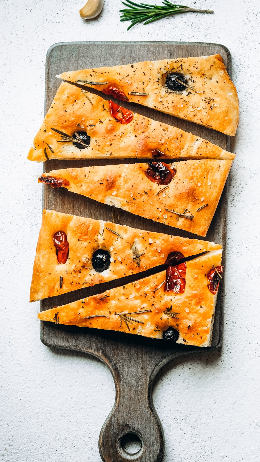 Overhead image of cut up focaccia arranged on a gray wooden board.