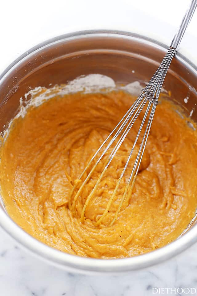 Whisking a muffin batter with pumpkin puree, flour, sugar, eggs, and spice.