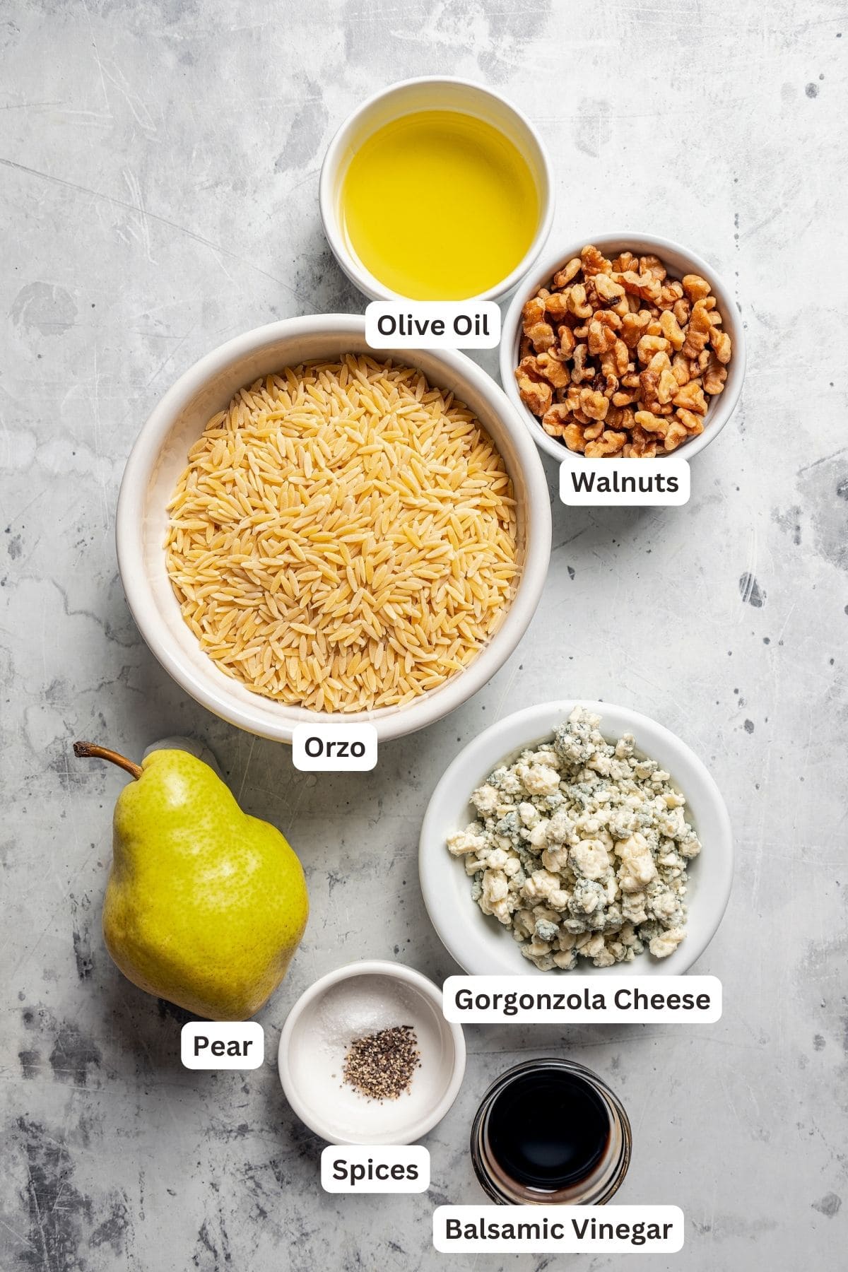 Ingredients for orzo salad with pears, walnuts, and gorgonzola cheese with text labels overlaying each ingredient.