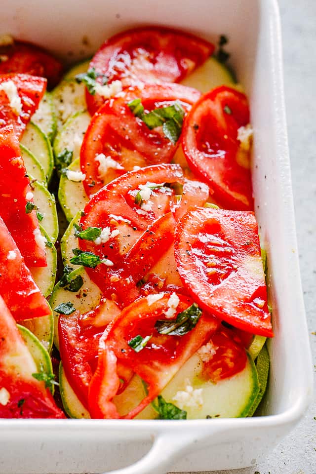 Layers of zucchini slices and tomato slices topped with garlic.