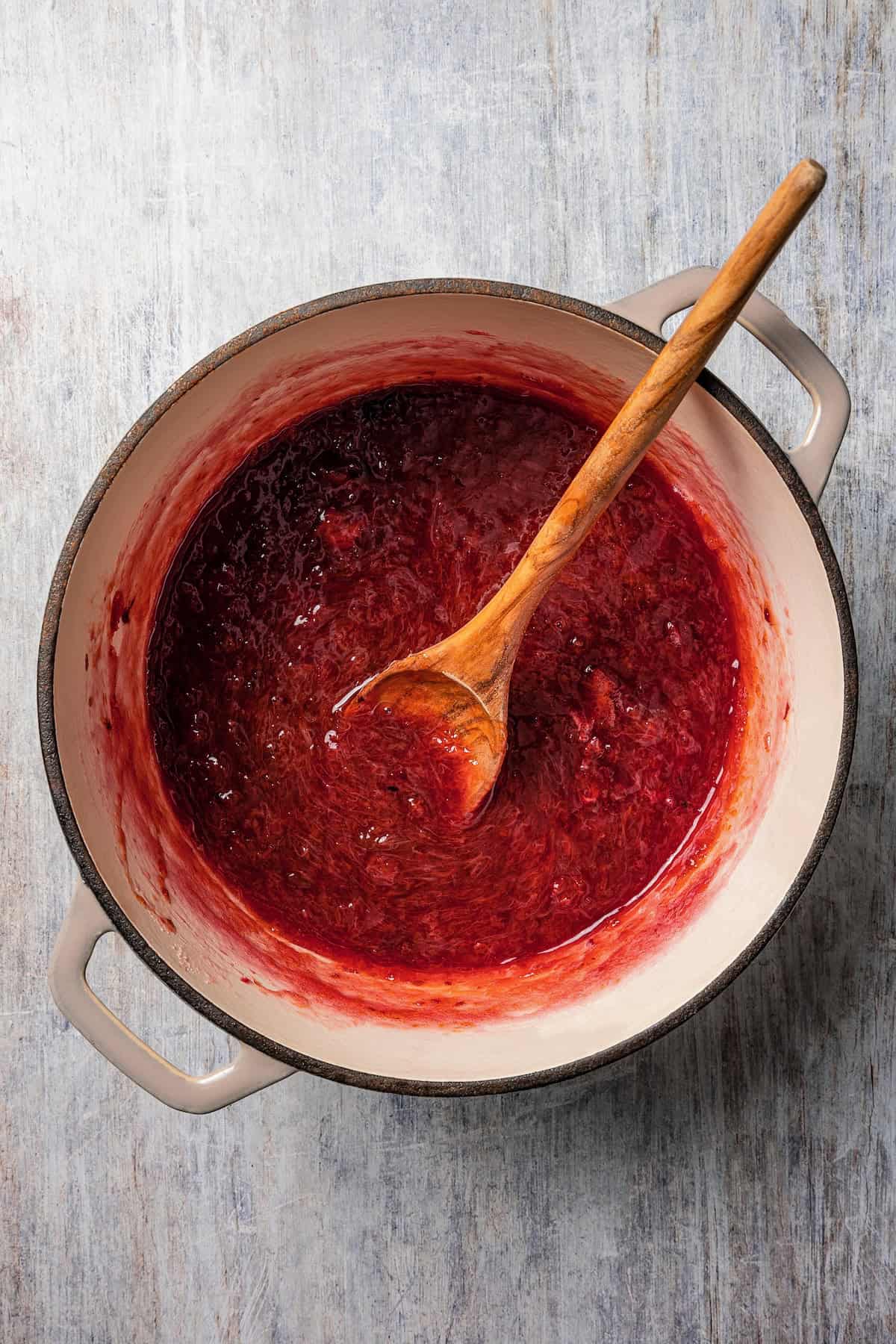 Homemade jam in a sauce pot with a wooden spoon.