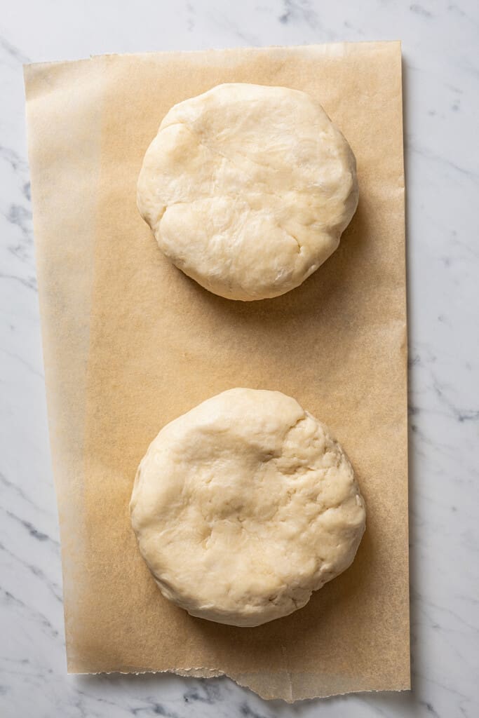 Overhead view of two disks of dough on a piece of parchment paper