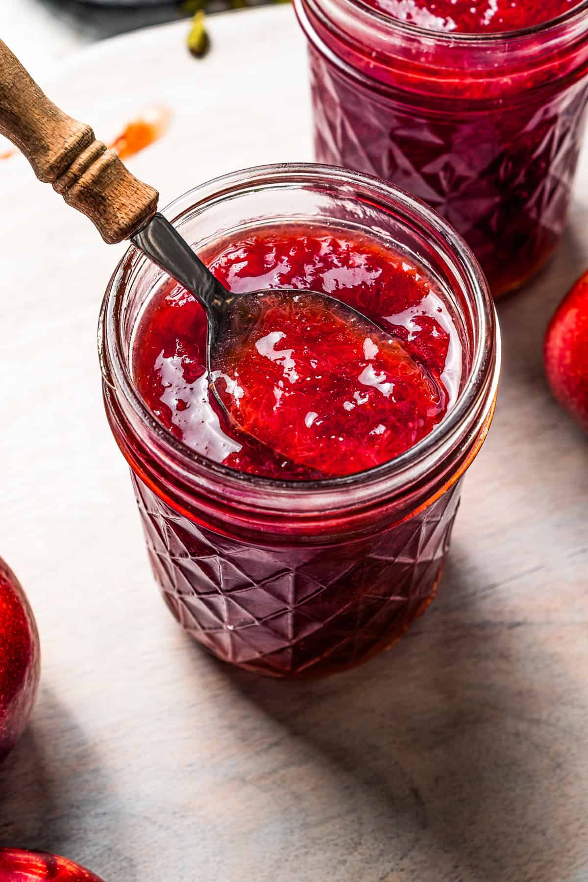 A spoon in a jar lifting out plum jam.