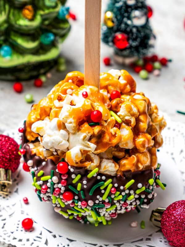 Homemade popcorn balls on a paper doily with plastic Christmas decorations in the background.