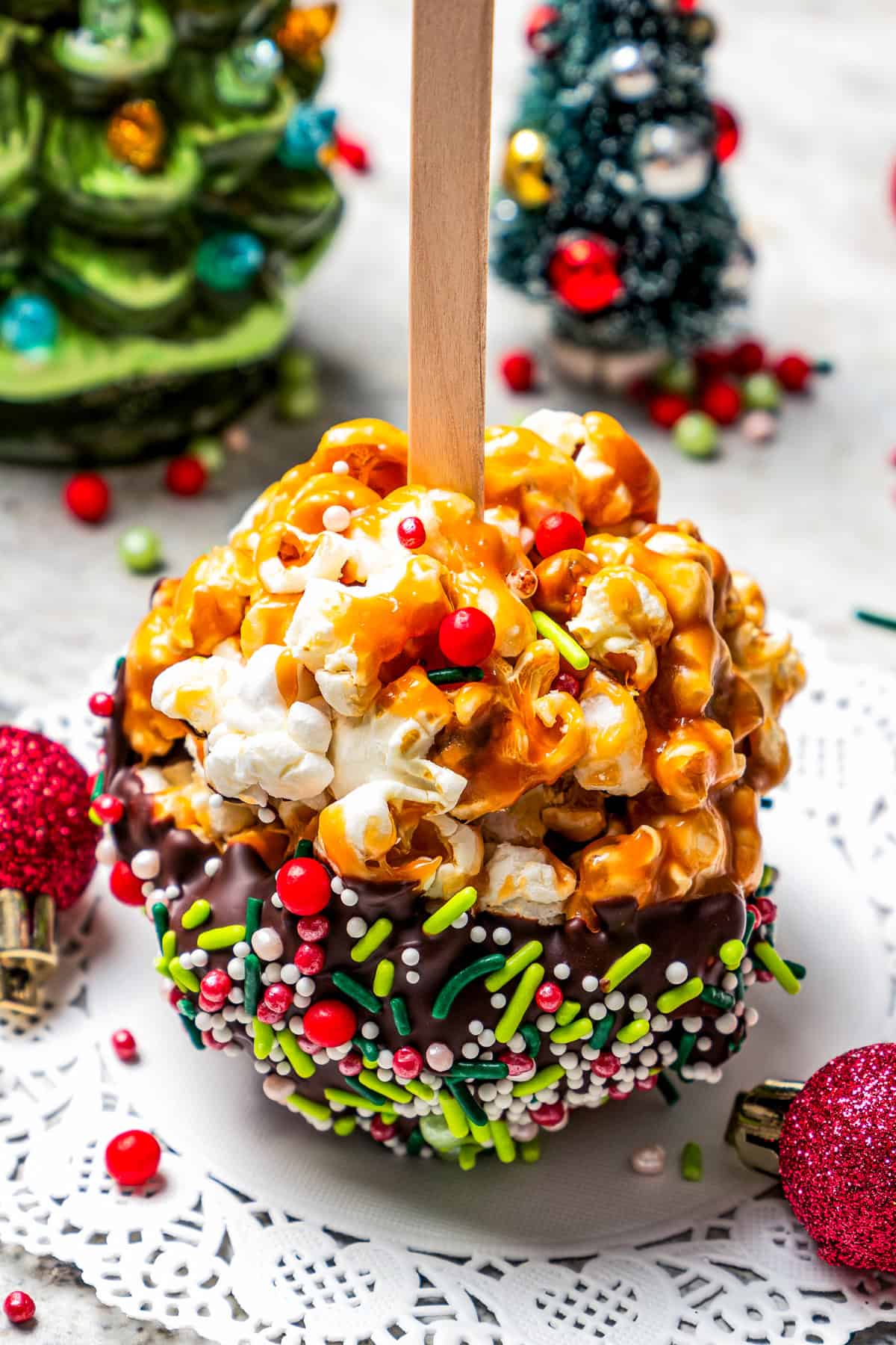 Homemade popcorn balls on a paper doily with plastic Christmas decorations in the background.