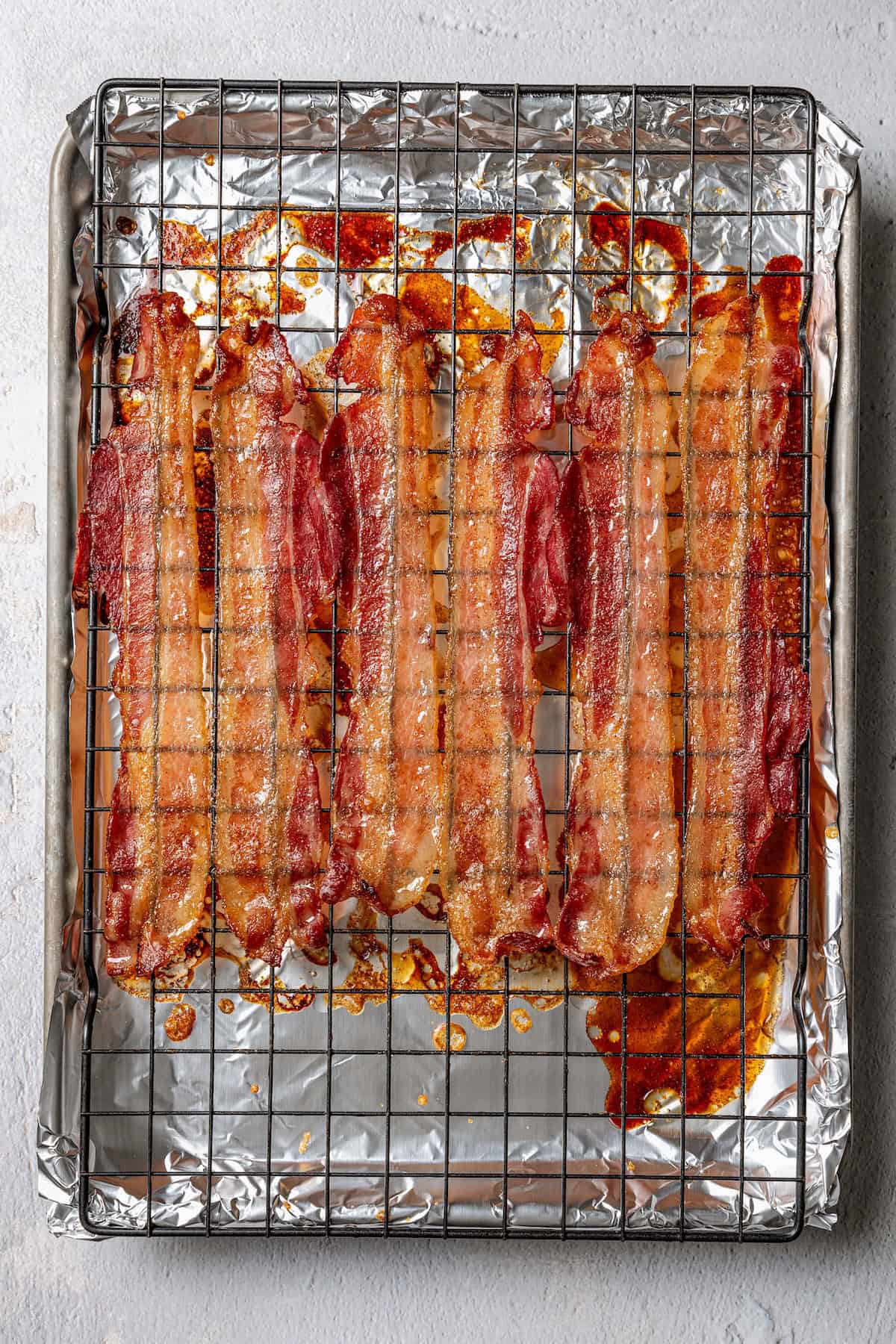 Cooked candied bacon on a wire rack set over a baking sheet.