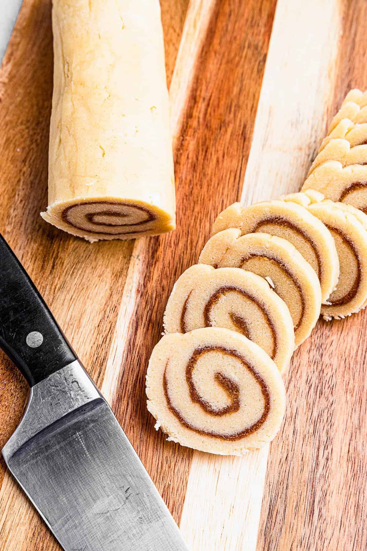 slicing raw cinnamon roll dough into cookies